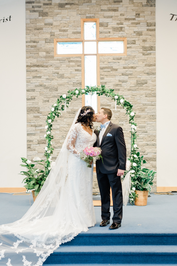 bride and groom kiss on a church altar