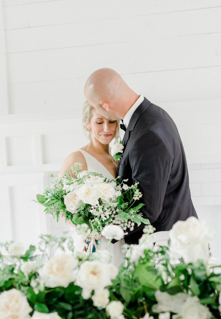 Groom kissing the bride's forehead at elegant wedding reception