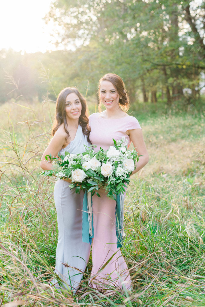 Bridesmaids in a field with gray and blush pink dresses and floral bouquets