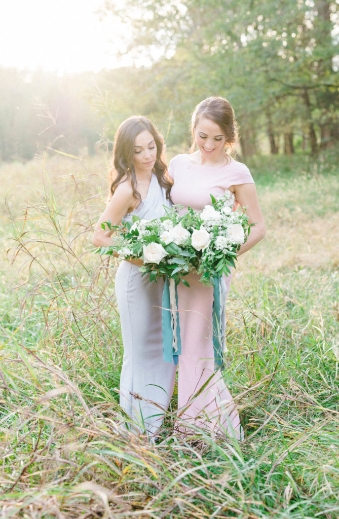 Bridesmaids in a field with gray and blush pink dresses and floral bouquets