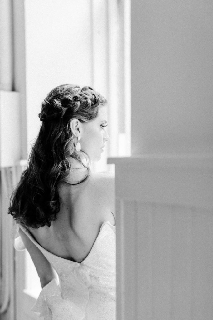 Bride looks longingly out of NYC loft window in elegant gown
