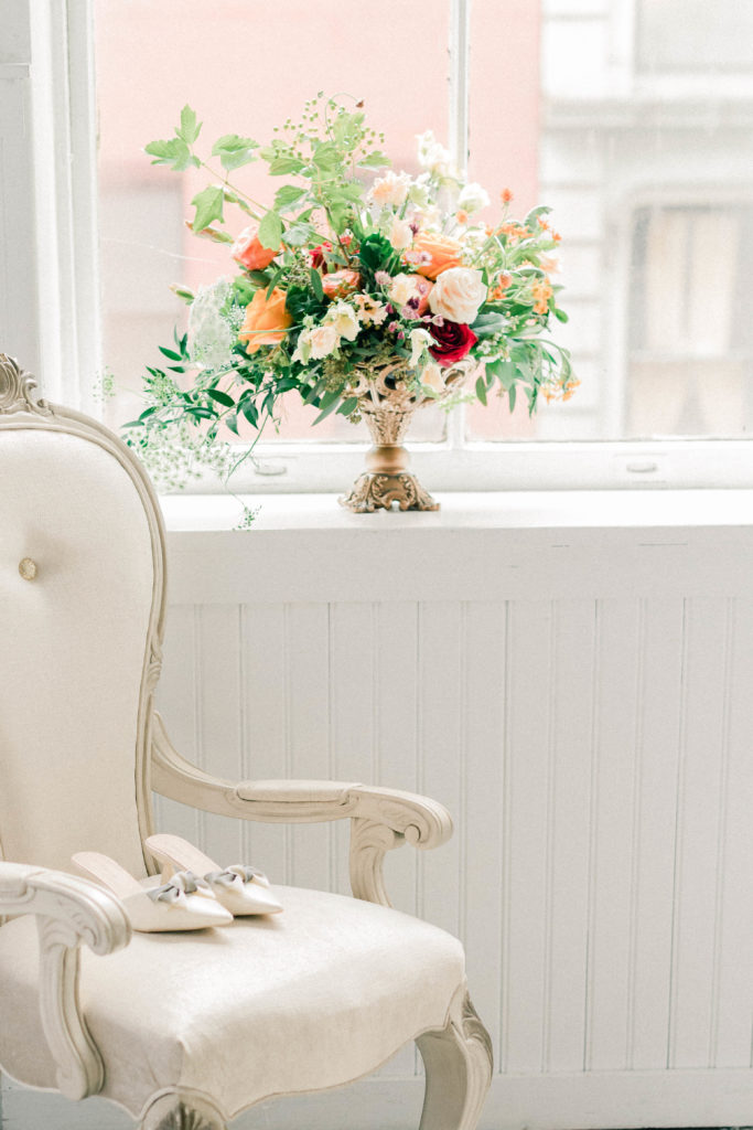 Elegant wedding floral arrangement with Victorian chair and bridal shoes