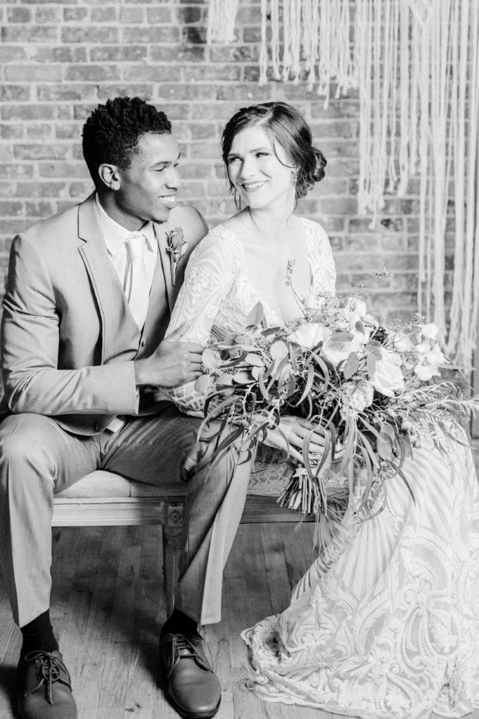 Bride and Groom sit on bench smiling