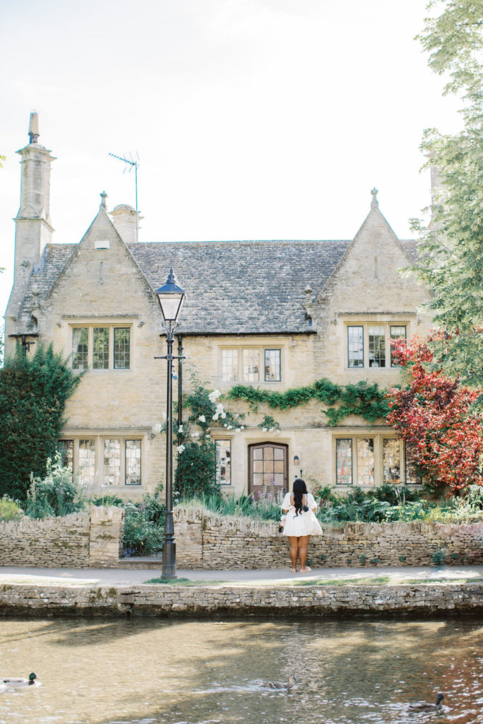 woman stands in burton on the water in the cotswolds, uk