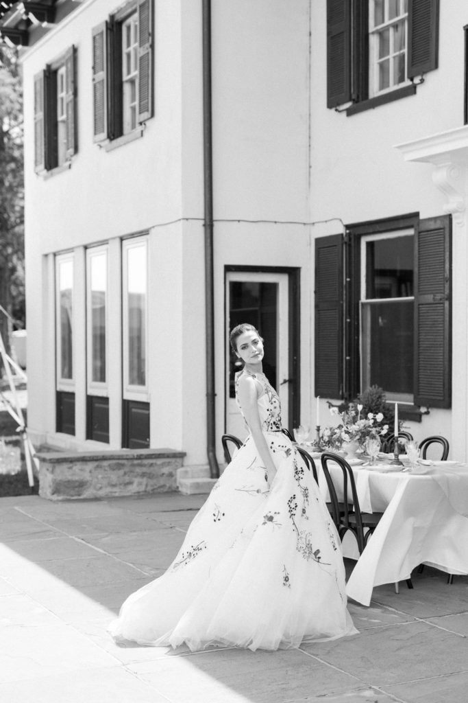 Bride stands on back patio reception during a summer wedding at The Willows Villanova 