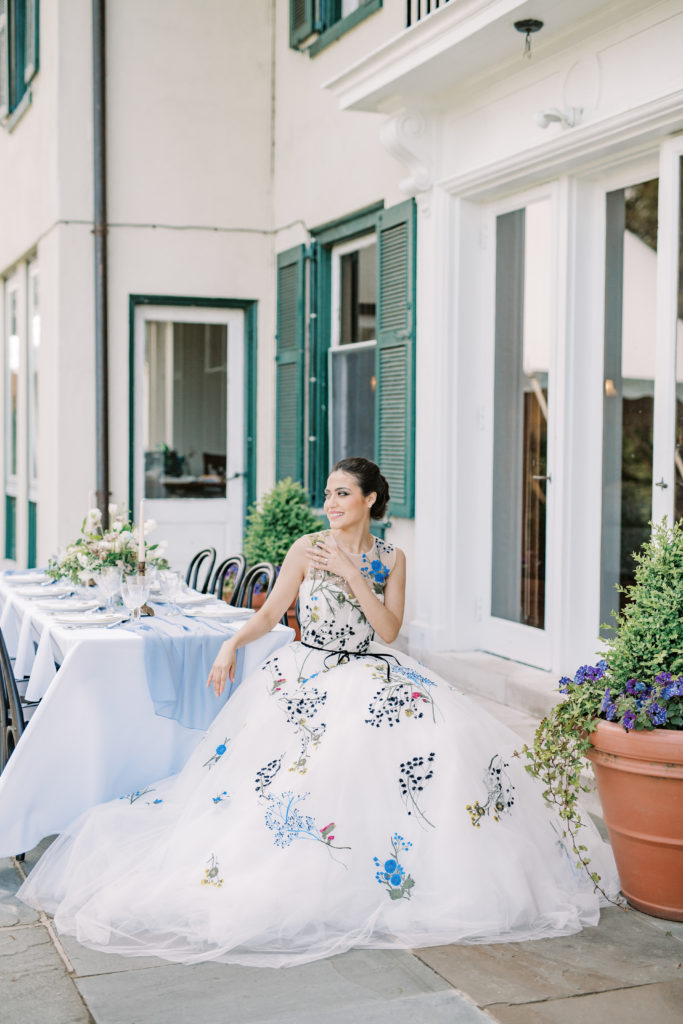 bride sits in the patio reception at the Willows Villanova in Philadelphia in a Monique Lhuillier gown