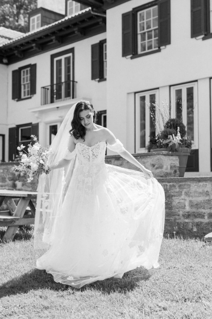bride walks  in field with the willows villanova mansion behind her