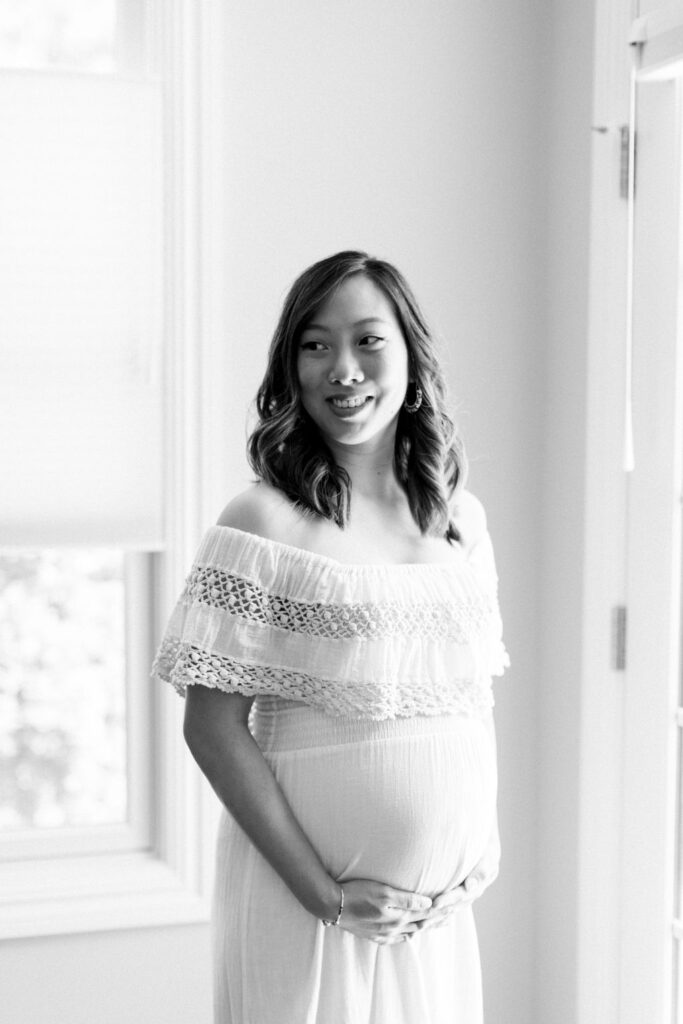 a mother is holding her pregnant belly and smiling during her at home maternity session